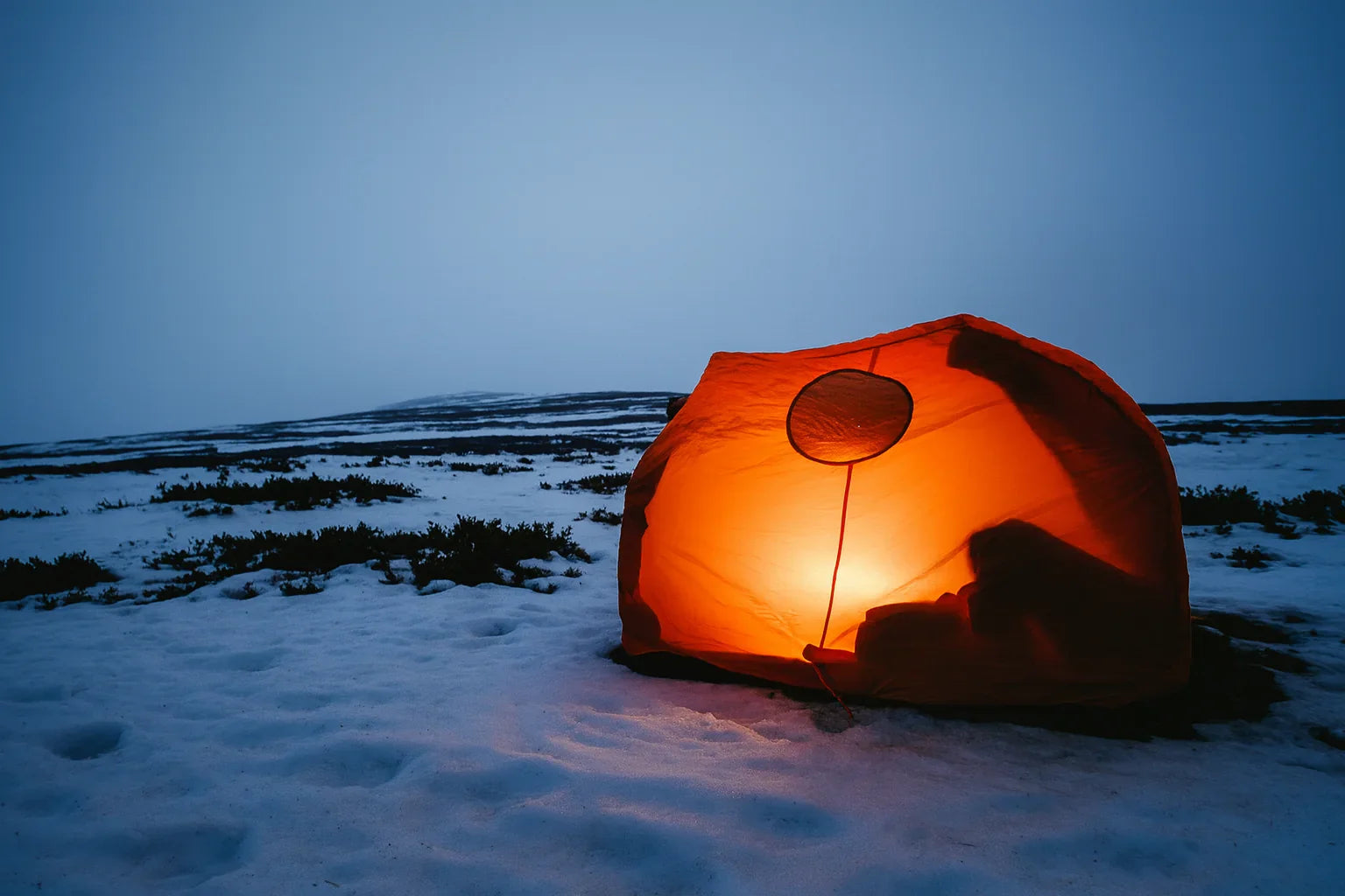 Abri de survie ultraléger pour bivouac en montagne enneigée.
