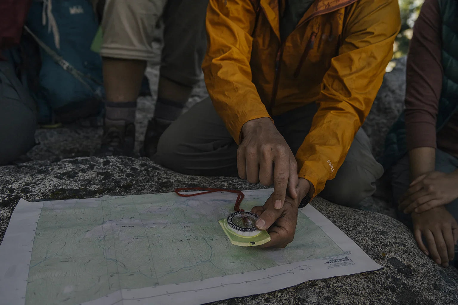 Groupe de randonneurs utilisant une boussole sur carte topographique.