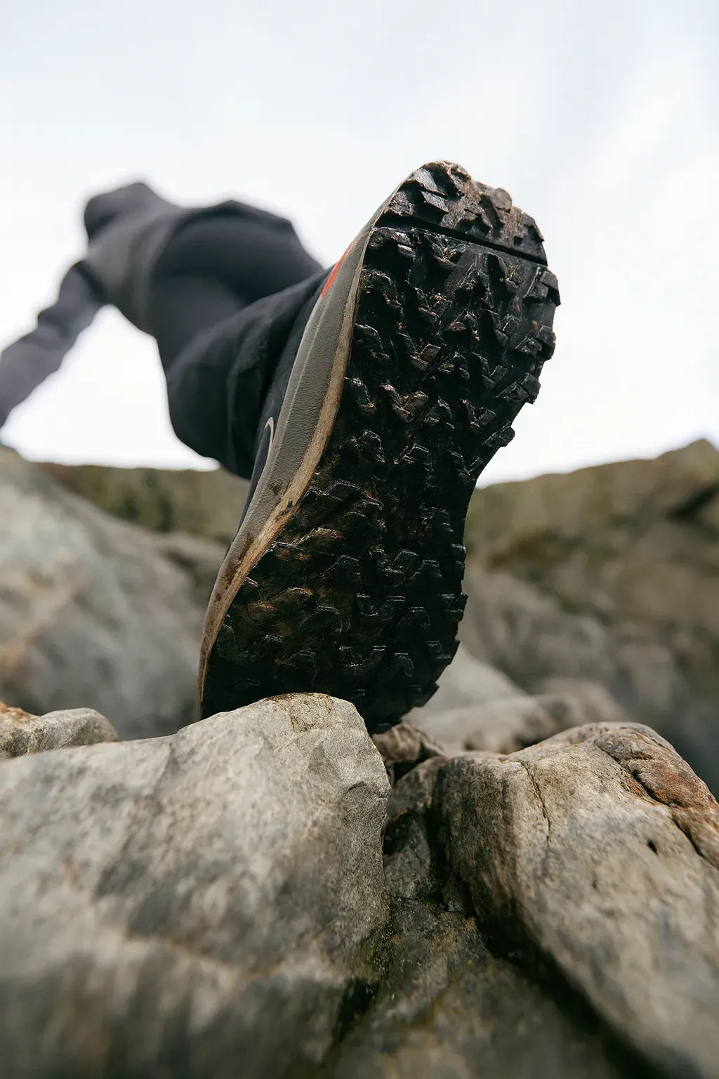 Semelle de chaussure de randonnée sur un rocher vue en contre-plongée.