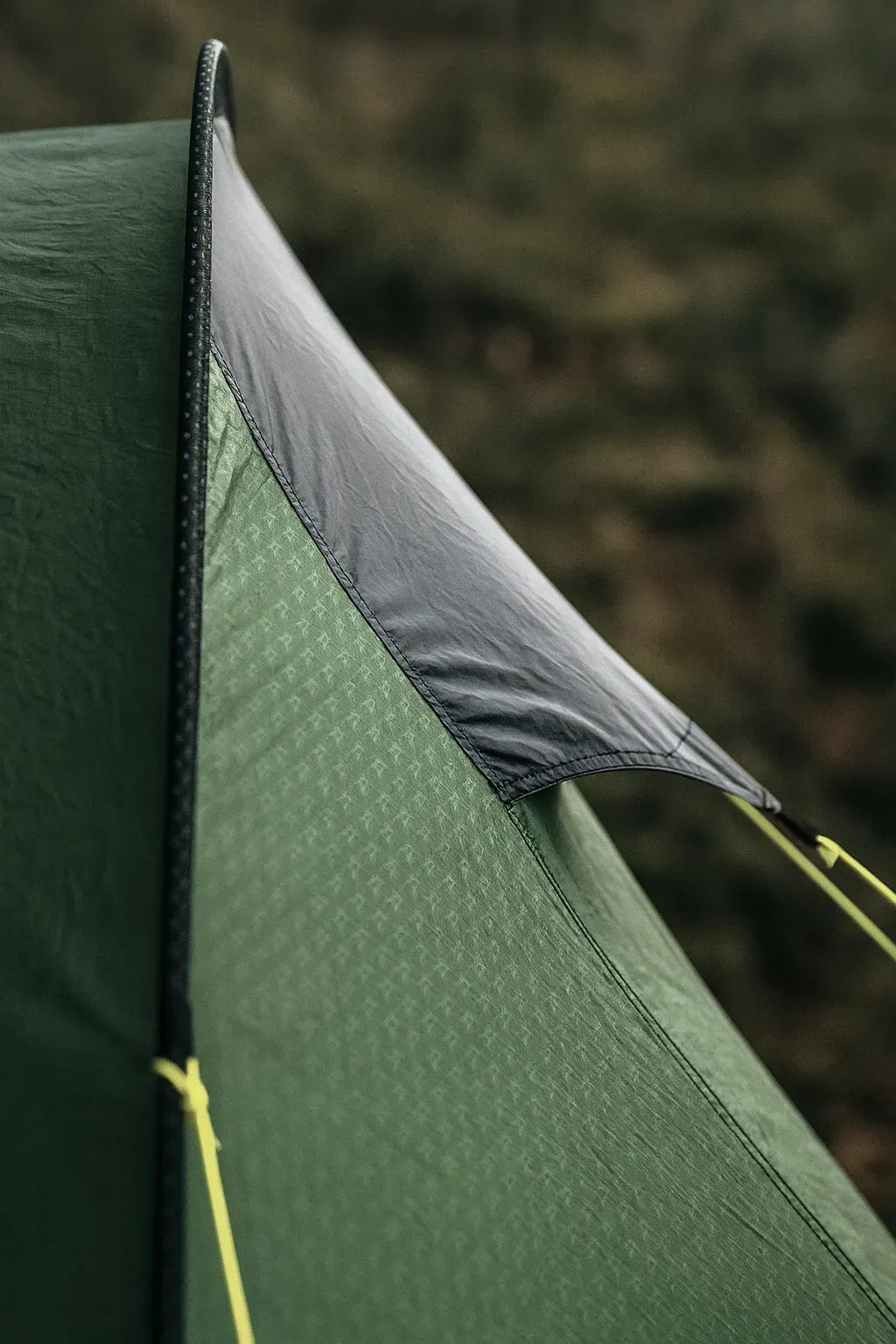 Détail de la toile extérieure d’une tente verte de camping.
