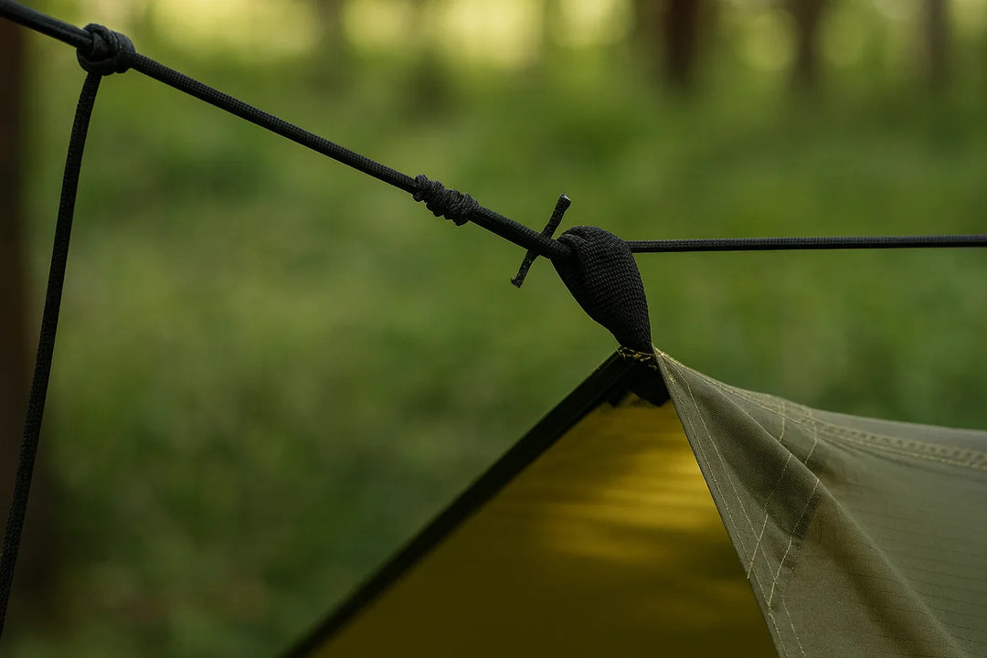 Détail d’un nœud de haubanage sur une tente ultralight de survie.