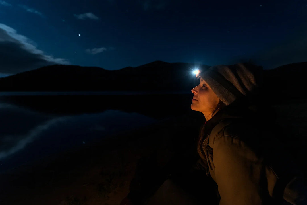 Femme portant une lampe frontale led en pleine nuit en randonnée.