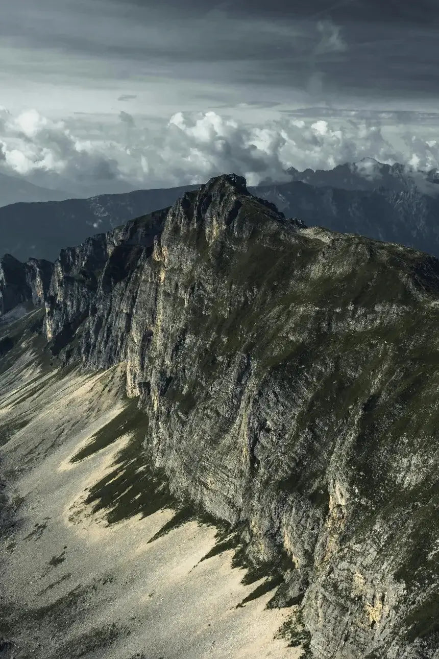 Crêtes rocheuses escarpées vues du ciel avec panorama alpin et ciel nuageux.