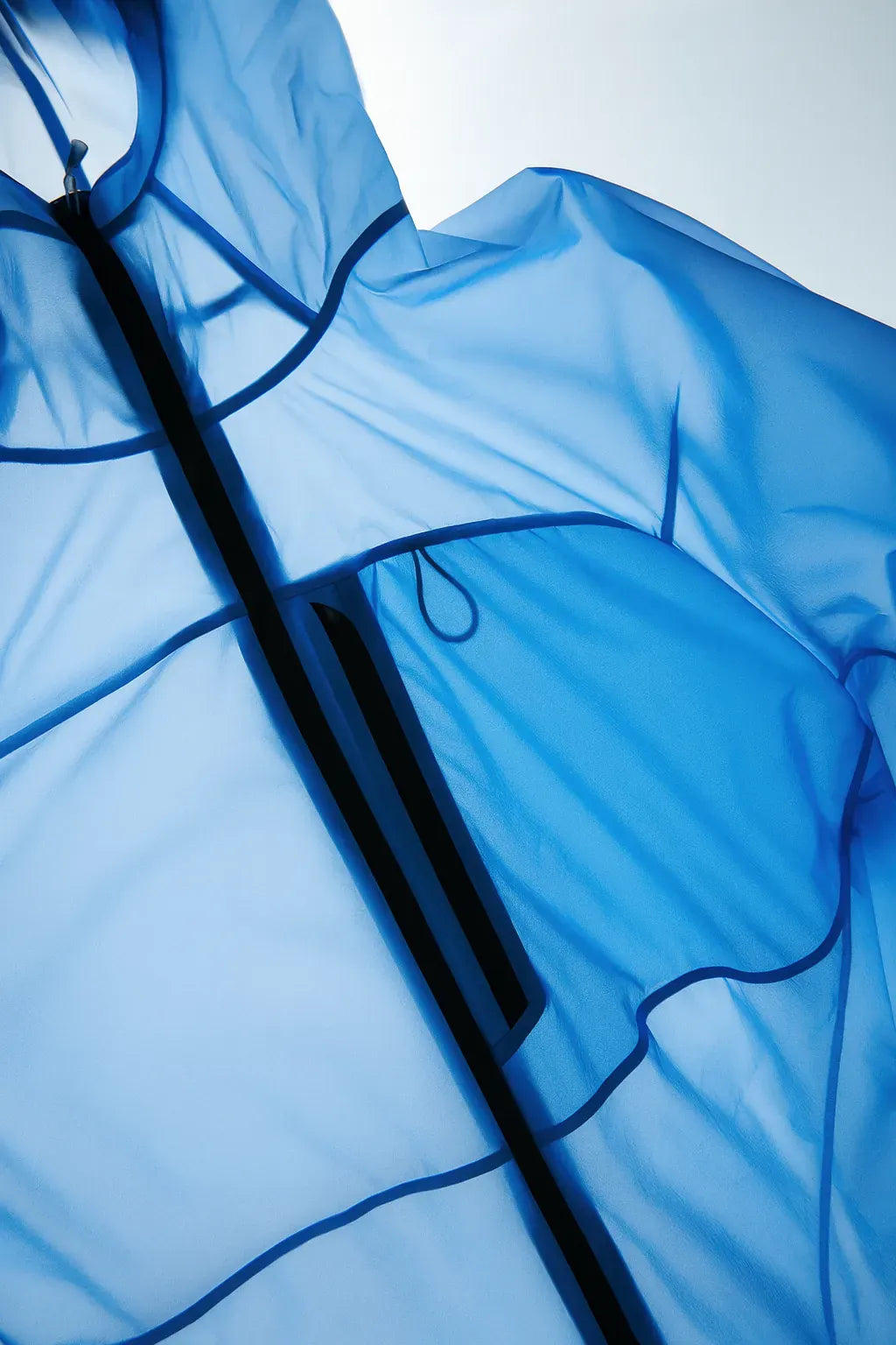 Détail d’une veste imperméable bleue translucide avec fermeture éclair.
