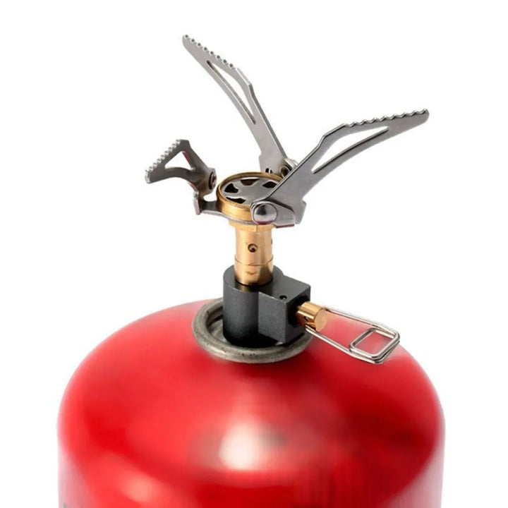 Réchaud de camping fixé sur une cartouche de gaz rouge, en vue contreplongée.