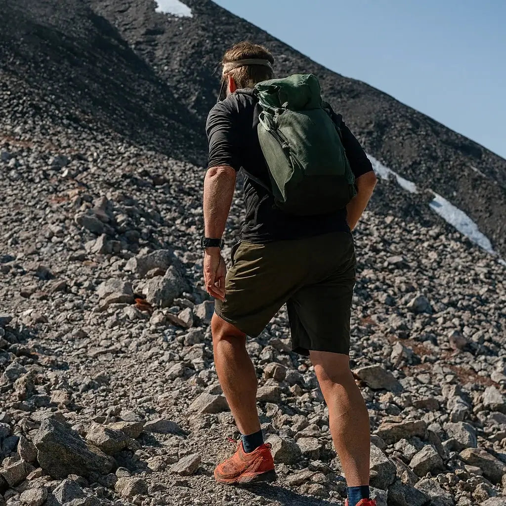 Randonneur en marche sur terrain rocheux avec sac à dos de trekking.