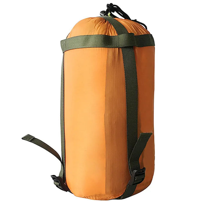 Sac de rangement compressible orange pour couchage en extérieur.