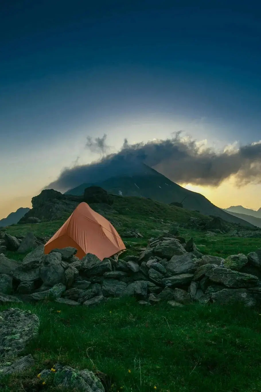 Tente de camping orangée isolée dans la montagne au crépuscule.