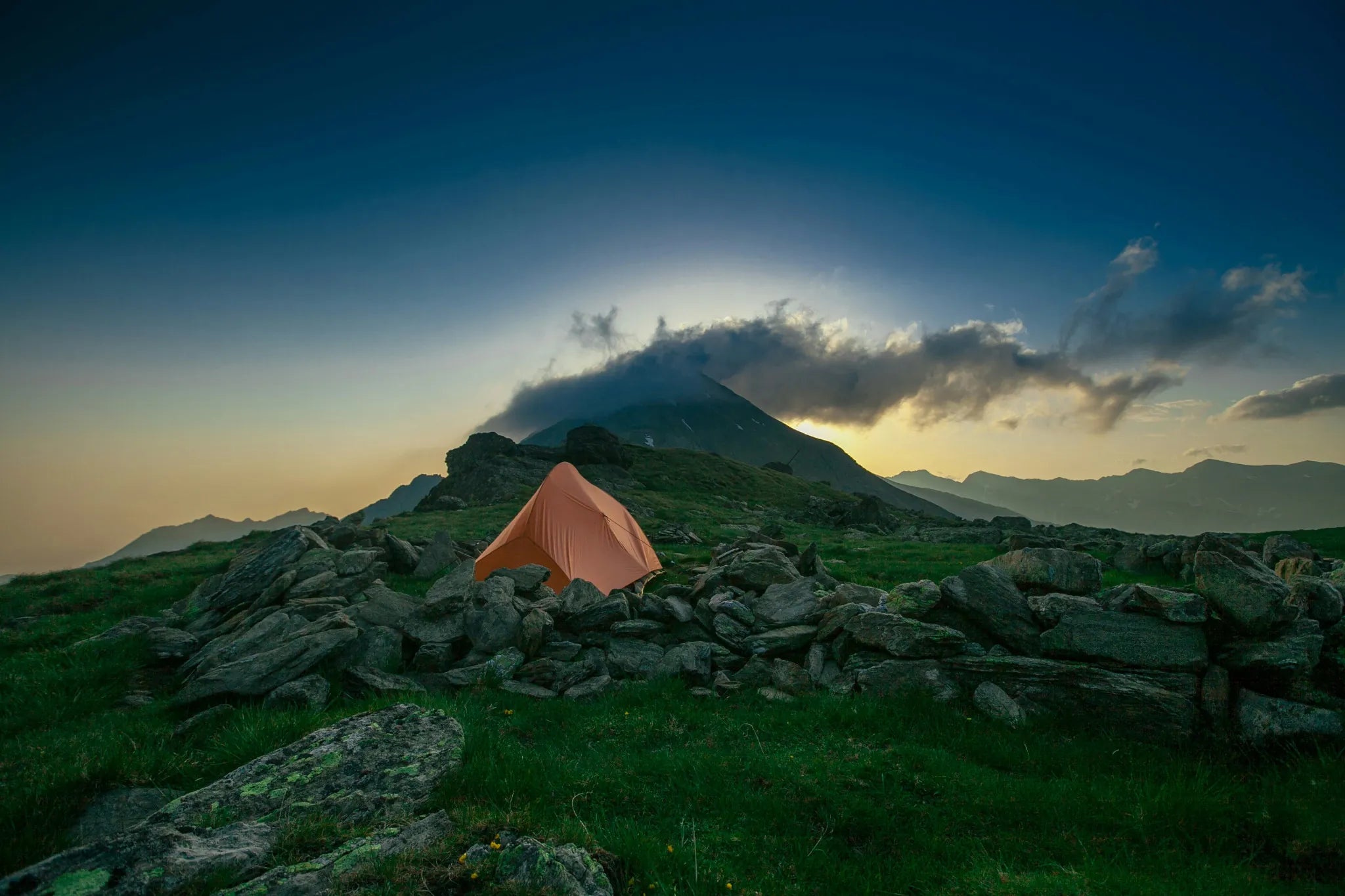 Tente de camping orangée isolée dans la montagne au crépuscule.